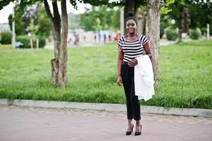 Young african american female doctor hold white coat on hand with a stethoscope posed outdoor. photo