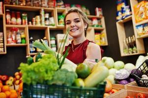 Girl in red holding different vegetables on fruits store. photo