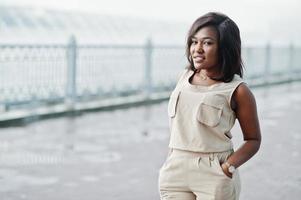 chica afroamericana en traje de café marrón posó al aire libre. mujer de negocios negra de moda contra la lluvia de fuentes. foto