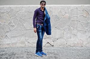 Young indian man on blue suit and sunglasses posed outdoor. photo