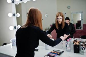 Make up artist work in her beauty visage studio salon. Woman applying by professional make up master. Beauty club concept. photo