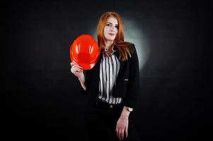 mujer ingeniera en casco de protección naranja sobre fondo negro de estudio. foto