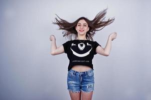 Portrait of an attractive girl in black t-shirt saying lol and denim shorts posing in the studio. photo