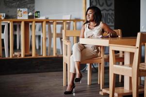 niña afroamericana sentada en el café y comiendo helado. foto