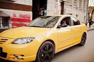 African american woman at violet dress and cap posed at yellow car. photo