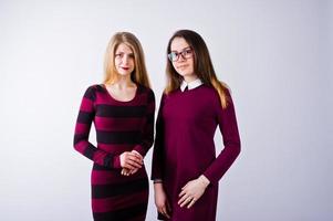 Portrait of two female friends in cherry dresses posing in the studio. photo