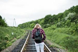 Portrait of a pretty blond girl in tartan shirt walking on the railway with map in her hands. photo