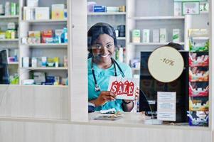 Two african american pharmacist working in drugstore at hospital pharmacy. African healthcare. Cashier holding sale. photo