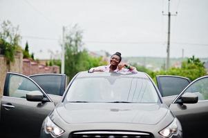 Rich business african woman in silver suv car on sunroof having fun. photo