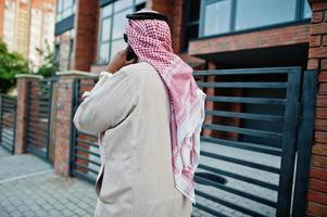 Back of Middle Eastern arab business man posed on street speaking on mobile phone. photo