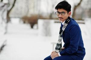 Stylish indian student man in suit, glasses and scarf posed at winter day outdoor. photo