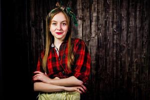 Young funny housewife in checkered shirt and yellow shorts pin up style on wooden background. photo