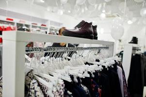 conjunto de ropa femenina en los estantes con zapatos en la tienda de ropa nueva boutique moderna. foto