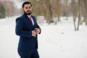 elegante hombre de negocios de barba india en traje posado en el día de invierno al aire libre. foto