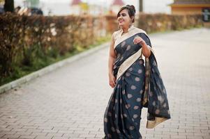 elegante morena chica india del sur de asia en sari bailando al aire libre. foto