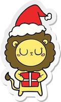sticker cartoon of a lion with christmas present wearing santa hat vector