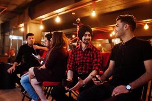 Group of indian friends sitting at lounge bar, smoke hookah and having rest. photo