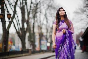 niña hindú india en el sari violeta tradicional posó en la calle. foto