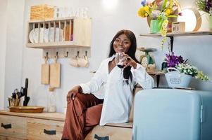 mujer afroamericana bebiendo vino en la cocina en su cita romántica. foto