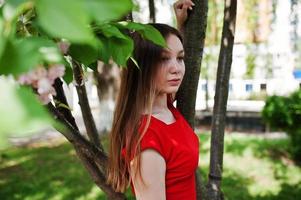 Teenage girl in red dress posed outdoor at sunny day. photo