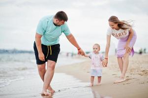 Summer vacations. Parents and people outdoor activity with children. Happy family holidays. Father, pregnant mother, baby daughter on sea sand beach. photo