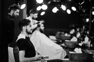 apuesto hombre barbudo en la barbería, peluquero en el trabajo. foto