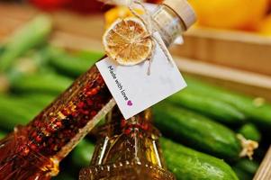 dos frascos de aceite de oliva virgen con condimentos en botella como la torre eifel en el estante con pepinos en el supermercado o tienda de comestibles. hecho con amor. foto
