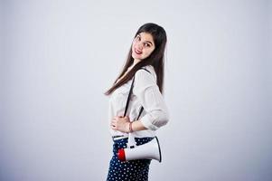 retrato de una mujer joven con pantalones azules y blusa blanca posando con megáfono en el estudio. foto