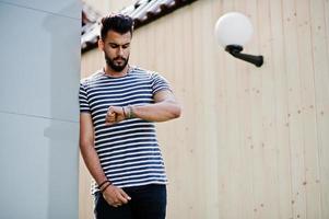 Handsome tall arabian beard man model at stripped shirt posed outdoor. Fashionable arab guy. photo