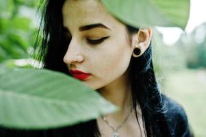 Sensual girl all in black, red lips and earlobe piersing. Goth dramatic woman. photo