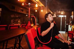 Asian man smoke hookah and having rest at lounge bar. photo