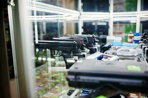 Different guns and revolvers on shelves store weapons on shop center.