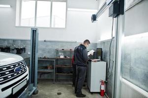 Auto mechanic sets american SUV car for diagnostics and configuration camber check in workshop of service station.. photo