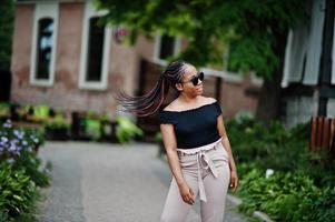 elegante mujer afroamericana en gafas de sol planteadas al aire libre. foto