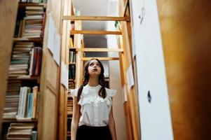 Girl with pigtails in white blouse at old library. photo