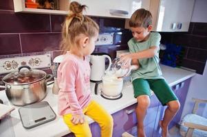 Kids cooking at kitchen, happy children's moments. Brother with sister together. photo