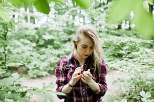 retrato de una atractiva chica rubia posando con una brújula en un bosque. foto