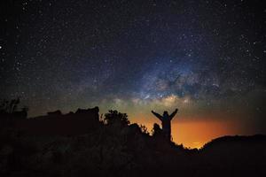 Landscape with milky way, Night sky with stars and silhouette of a standing happy man on the mountain at Doi Luang Chiang Dao. photo