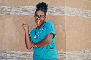 African american doctor female at lab coat with stethoscope posed outdoor against clinic. photo