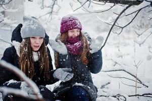 dos amigas divertidas divirtiéndose en el día de invierno cubierto de nieve cerca de árboles cubiertos de nieve. foto