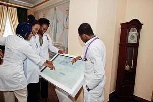 grupo de estudiantes de médicos africanos dentro de la universidad médica cerca de la mesa de información. foto