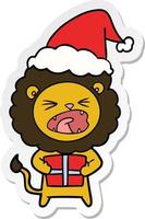 sticker cartoon of a lion with christmas present wearing santa hat vector