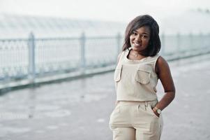 African american girl in brown coffee suit posed outdoor. Fashionable black business woman against rain of fountains. photo