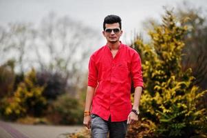 hombre indio con camisa roja y gafas de sol posó al aire libre. foto