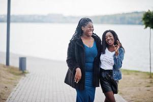 dos amigas afroamericanas de piel oscura. una de ellas modelo talla grande, la segunda slim. divertirse y pasar tiempo juntos. foto