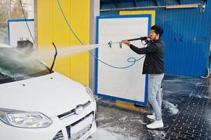 hombre del sur de asia o hombre indio lavando su transporte blanco en el lavado de autos. foto