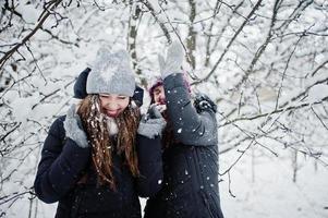 Two funny girls friends having fun at winter snowy day near snow covered trees. photo