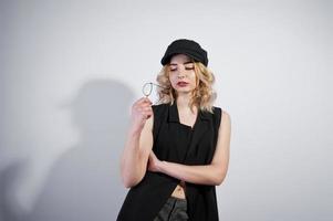 Studio portrait of blonde girl in black wear and cap against white background. photo