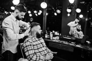 apuesto hombre barbudo en la barbería, peluquero en el trabajo. foto