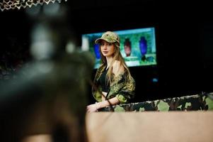 niña militar en uniforme de camuflaje contra el fondo del ejército en el campo de tiro. apuntar a la gente. foto